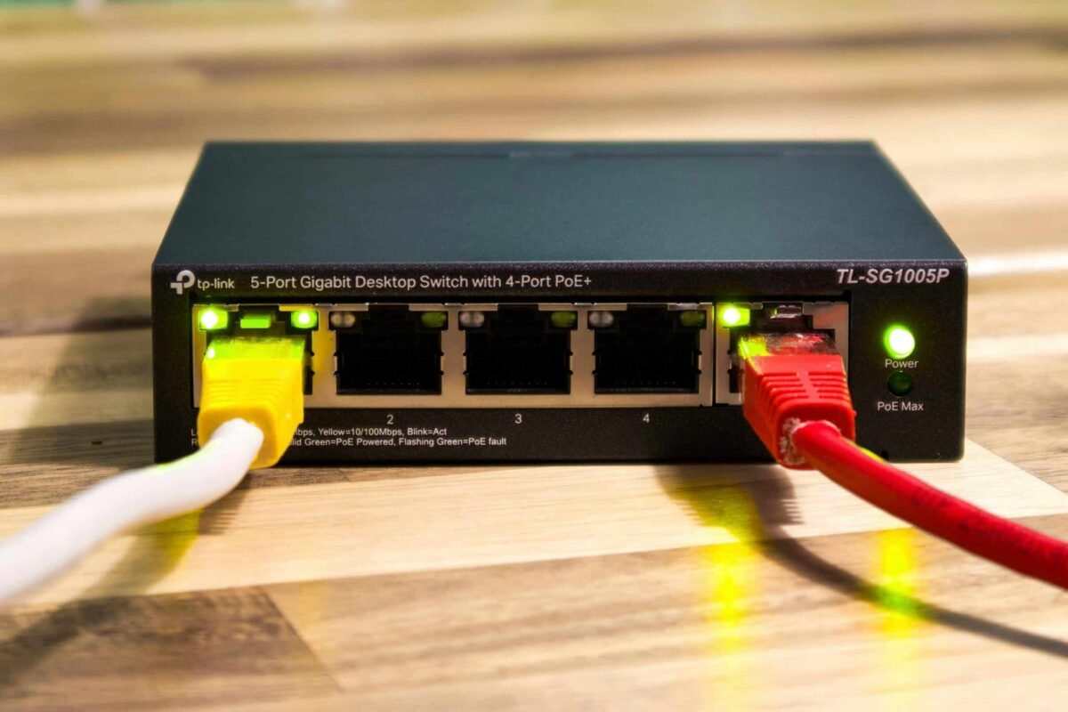 Close-up of a TP-Link Ethernet switch with yellow, red, and white cables connected.