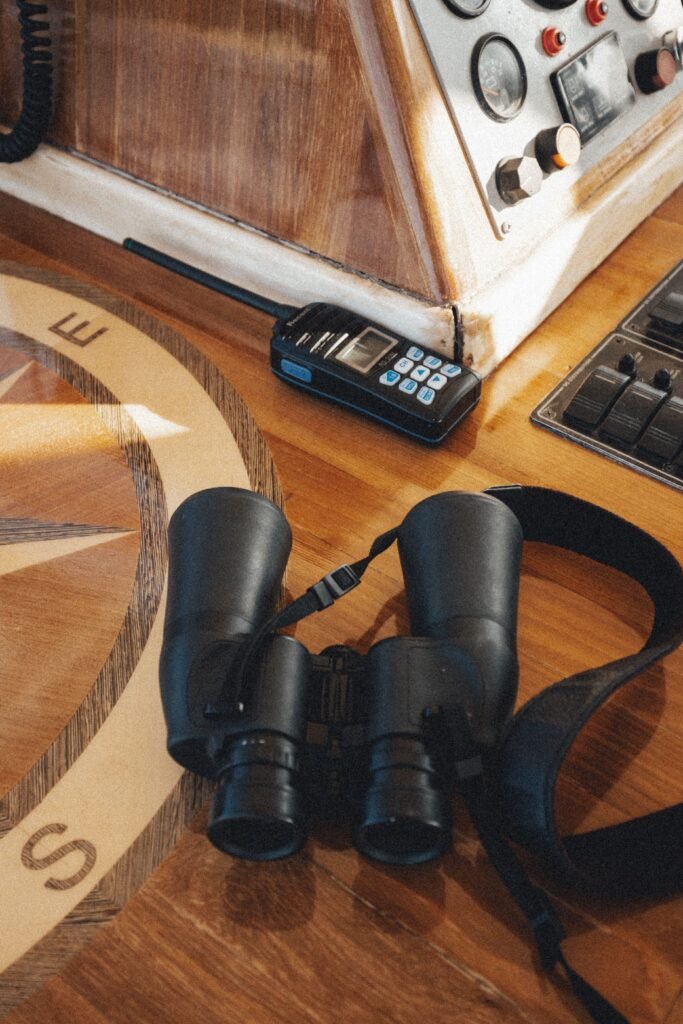 Binoculars and radio on a nautical compass in boat cockpit.